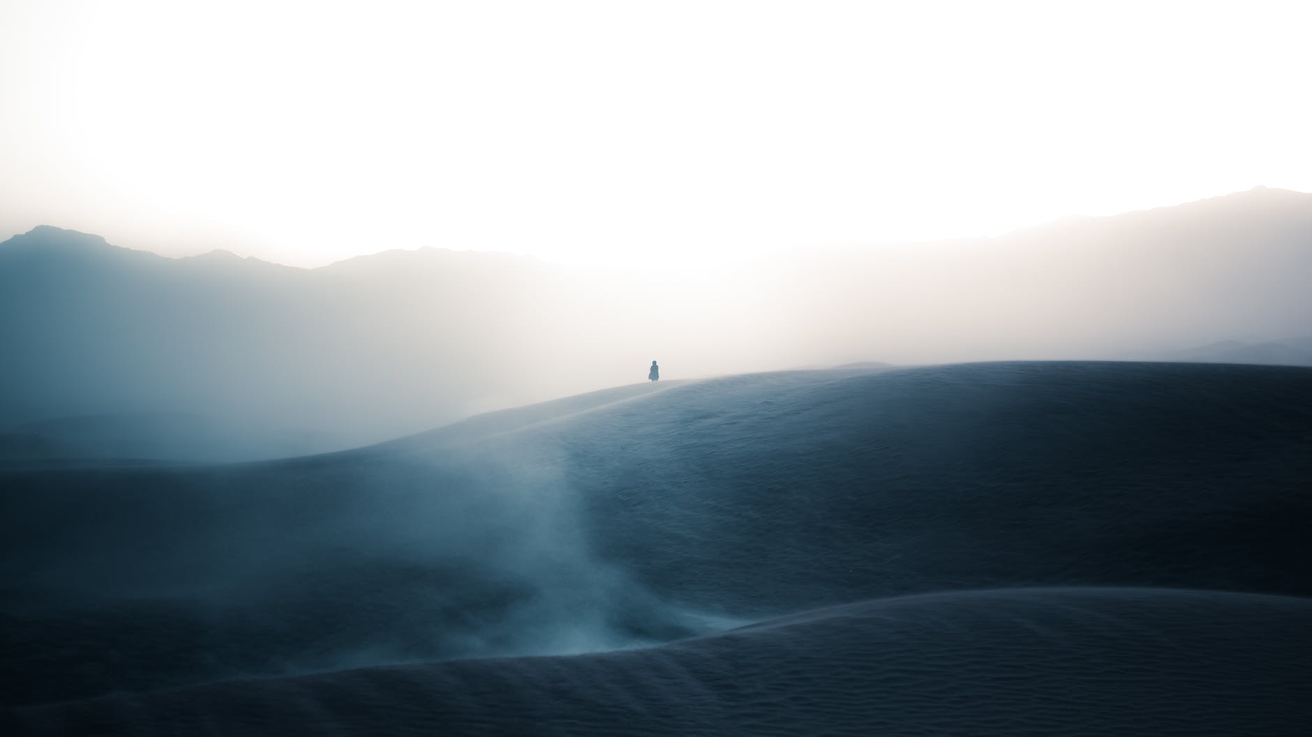 silhouette of a person on a desert in distance